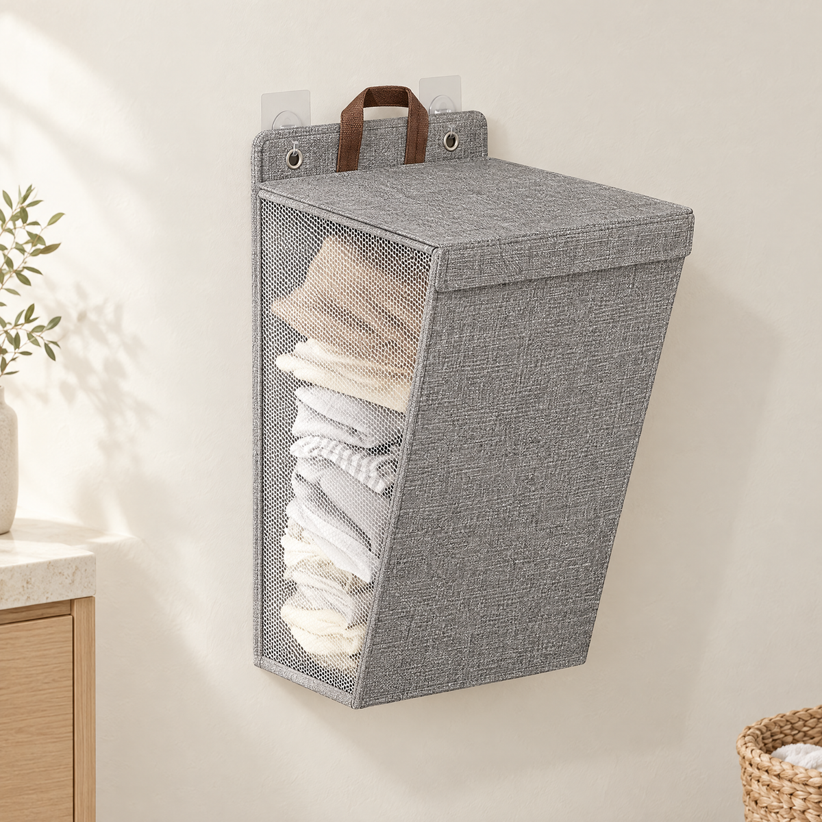 Grey wall-hanging laundry hamper with lid closed, mounted on a warm off-white wall